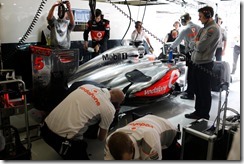 The team work on the car of Jenson Button in the garage.